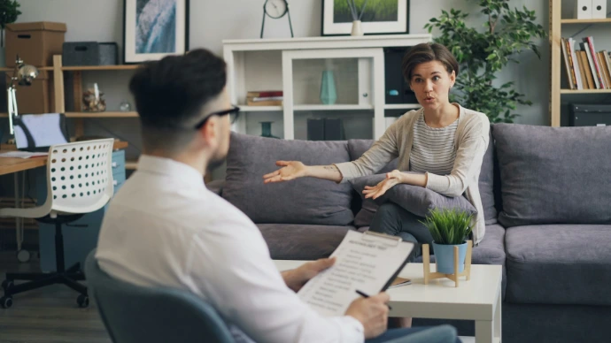 a man sitting on a couch talking to a woman
